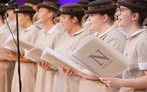Norland students in a choir singing on a stage holding choir books