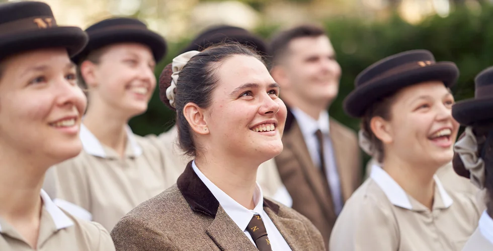 A female Norland Nanny student in a blazer looking up and smiling