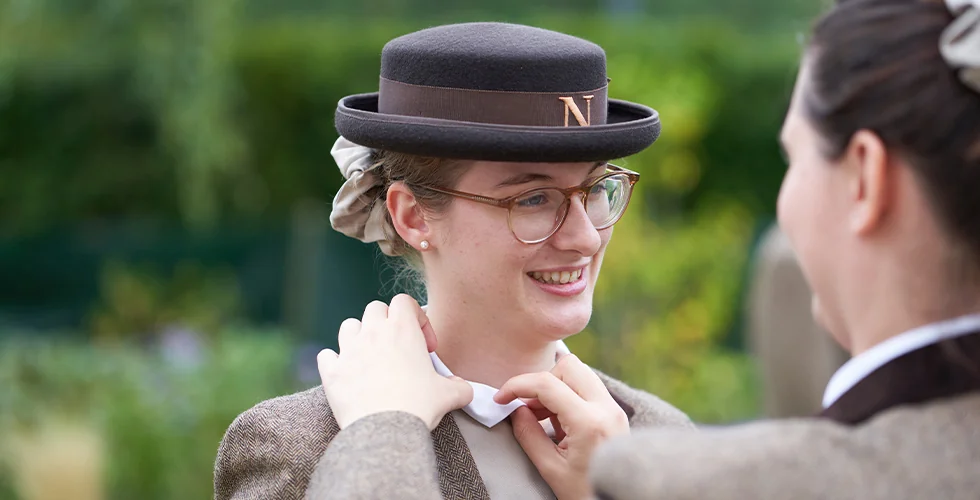 Two Norland students adjusting each other's formal uniform