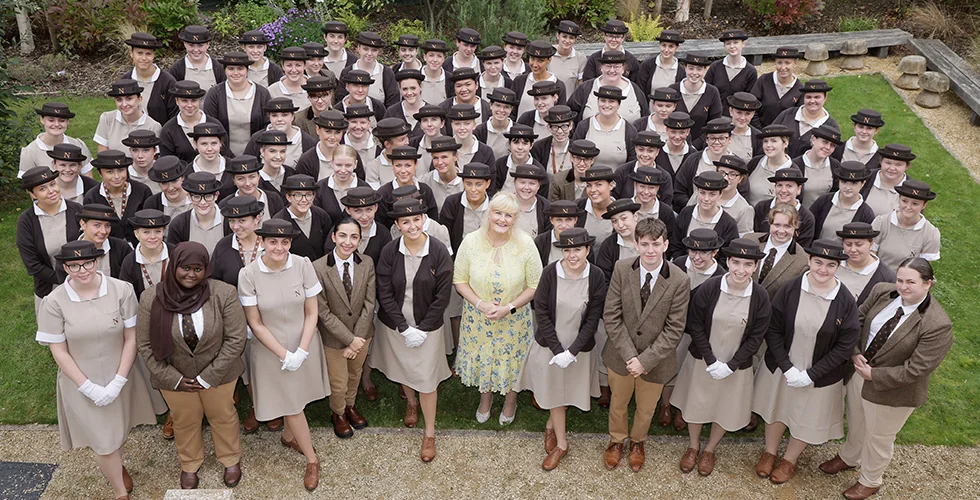 Norland Nanny students in their formal uniform with Dr Janet Rose, Norland Principal