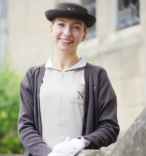 Norland student in formal uniform in front of building smiling