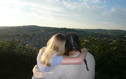 Students hugging at viewpoint looking out over the city of Bath