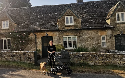 Student with pram stood outside of cotswold house in sunshine