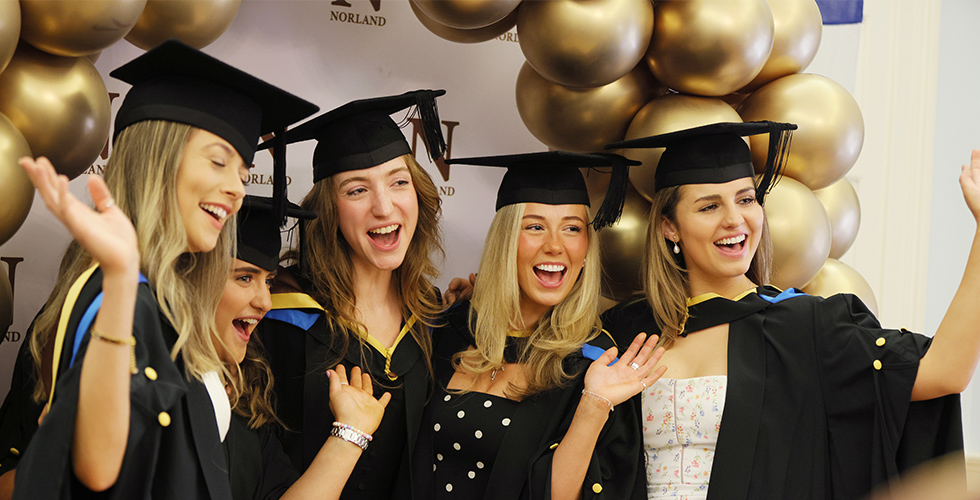 Graduates in robes posing for photo at their graduation