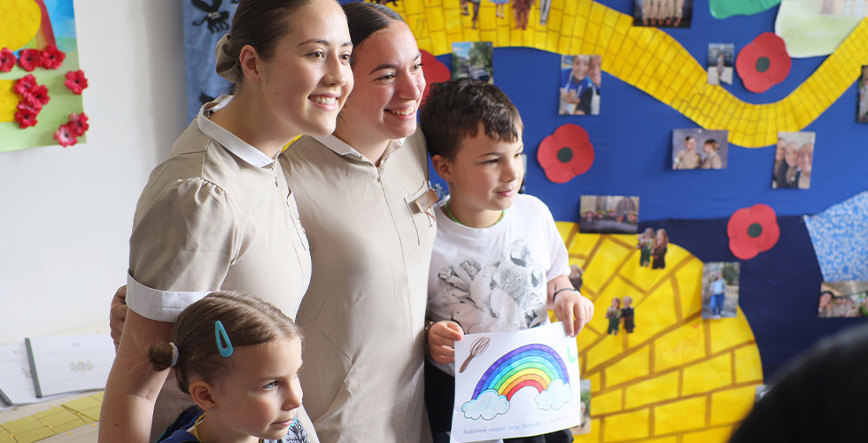 Norland students in uniform posing for photos with children