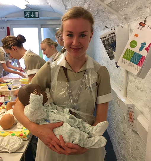 Student in formal uniform holding baby doll