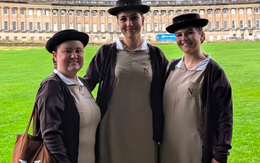 Three Norland students in their uniform stood in front of the Royal Crescent