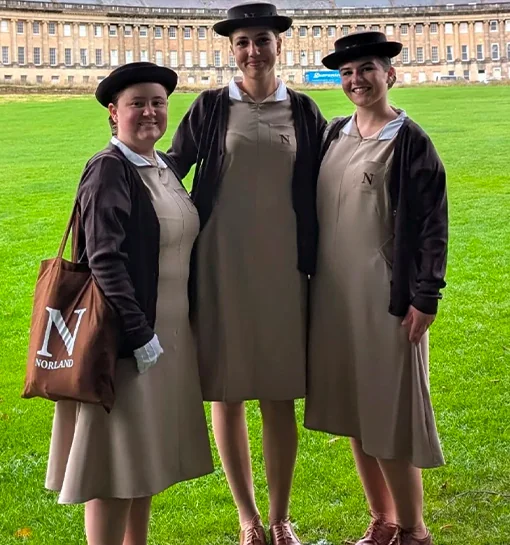 Three Norland students in their uniform stood in front of the Royal Crescent