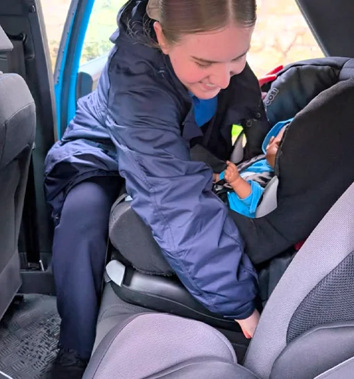 A Norland student fitting a car seat in a car
