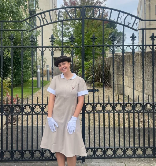 Norland student in formal uniform stood outside of Norland gates