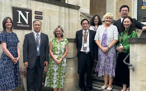 A group of people from Norland and Beijing Yaoyang Foundation stood on steps outside Norland in Bath