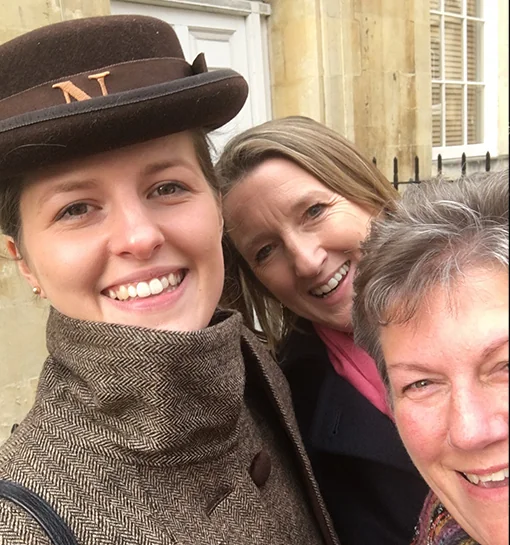 A Norland Nanny in her formal uniform with two ladies smiling