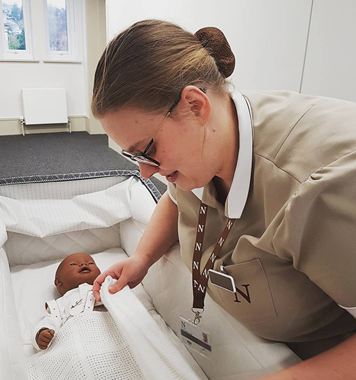 Norland student swaddling doll in uniform