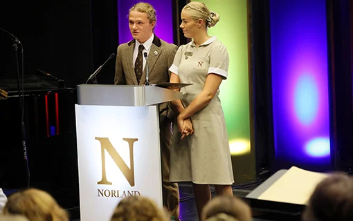 A male and a female Norland student standing at a plinth speaking into a microphone