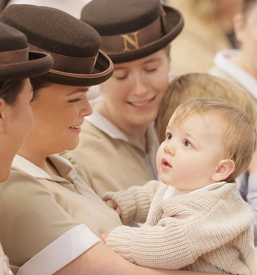 Norland students in uniform holding baby