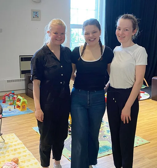 Three females stood in a room smiling after volunteering