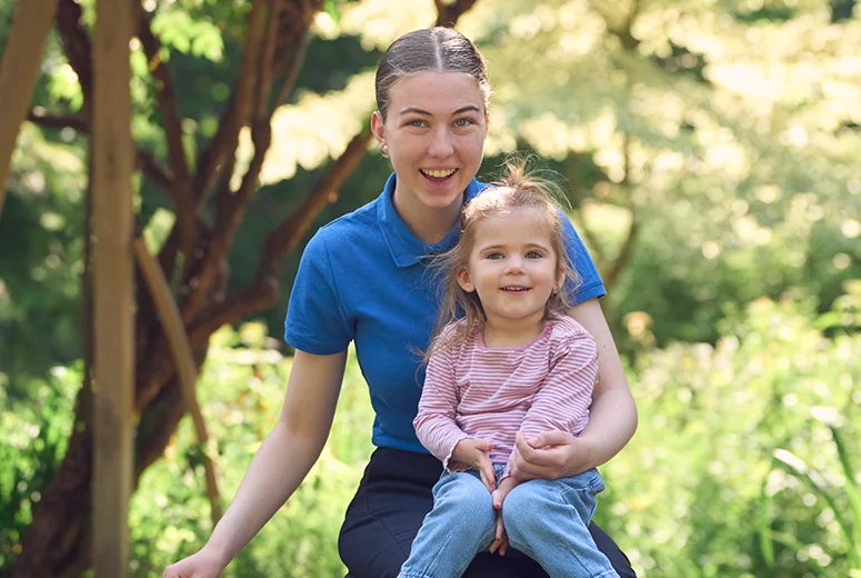 A female Norland Nanny student sat with a child on her lap