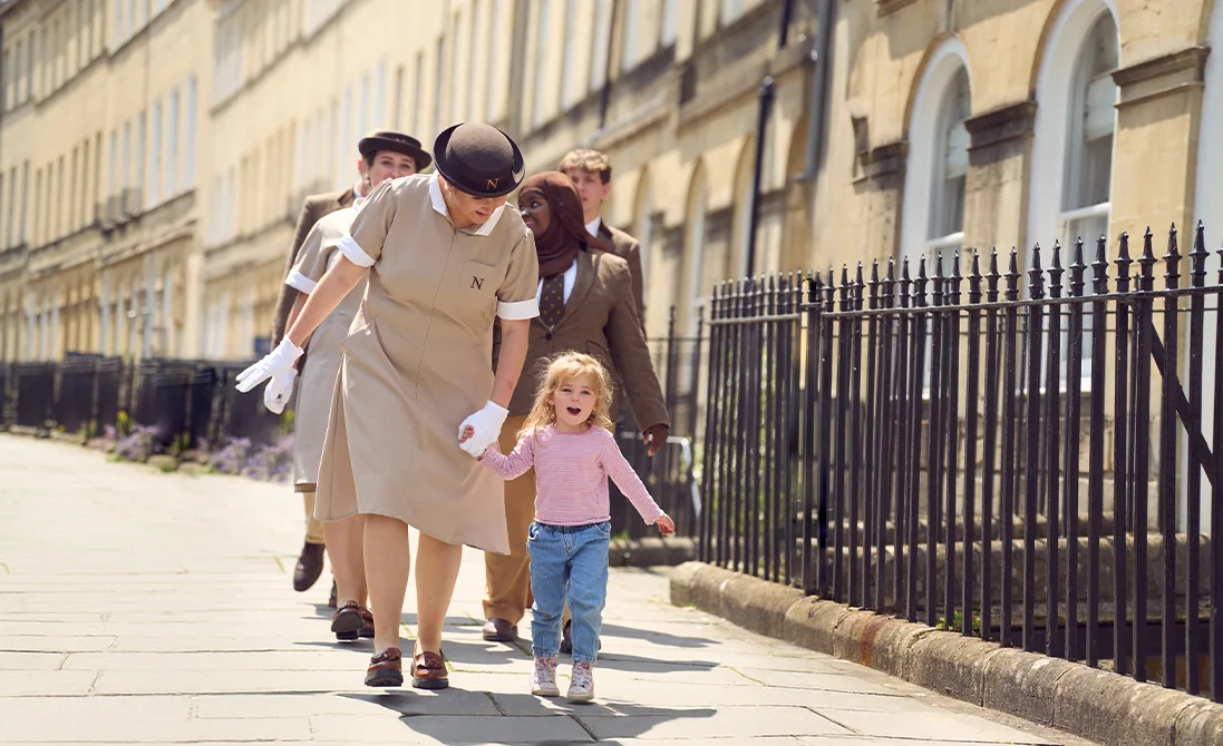 A group of Norland Nannies walking through a Georgian street in Bath, UK with a child