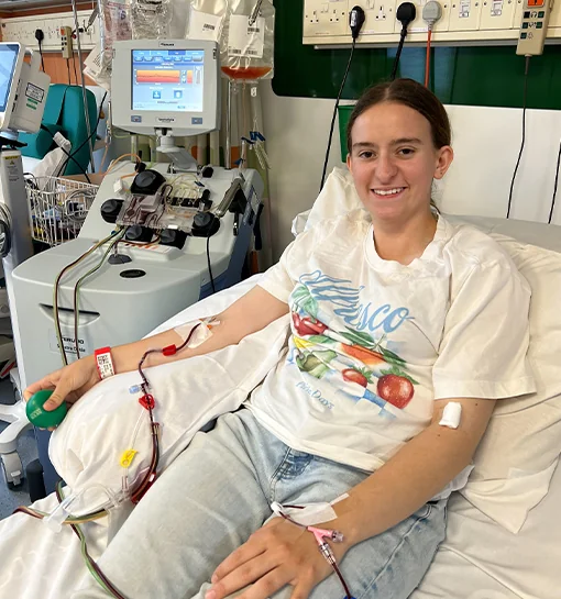 A female smiling in a hospital bed after donating stem cells
