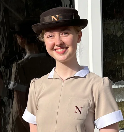 Norland student in uniform smiling outside of home