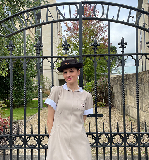 Student in Norland uniform smiling outside of Norland College gates