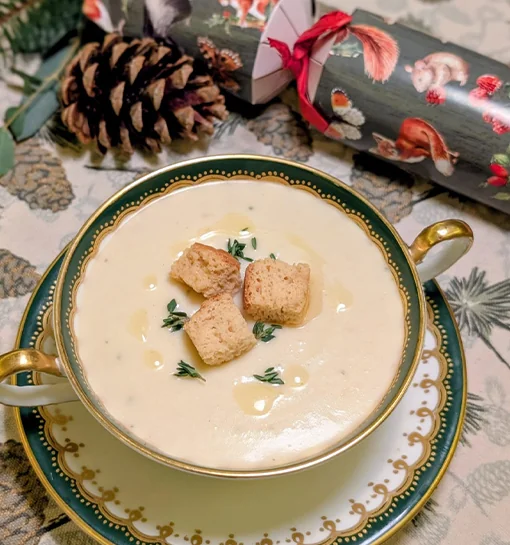 A soup on a dinner table with a Christmas cracker