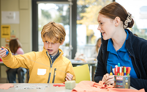 Norland student with child demonstrating sewing