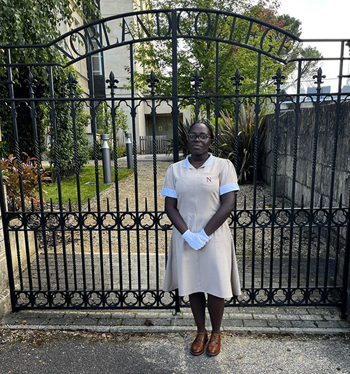Student in formal uniform posing outside of the Norland gates
