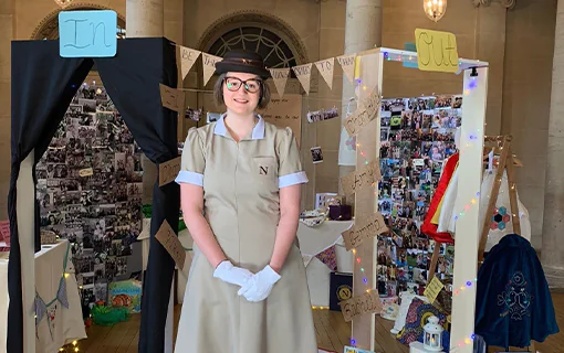 A Norland Nanny in uniform stood in front of a display at the Bath Assembly Rooms