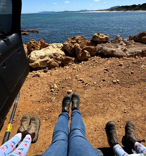 An adult and two children sat in the back of a car with their legs outstretched in front of the sea