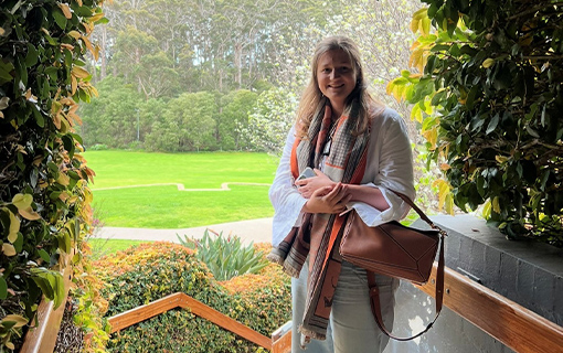 A female stood smiling in front of a garden