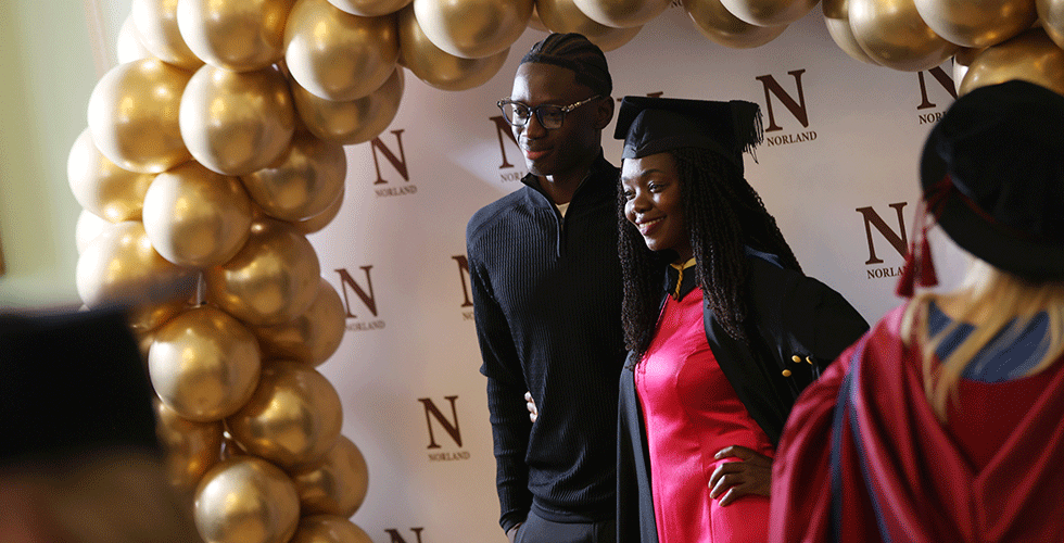 Norland degree graduate smiling for picture in front of balloons