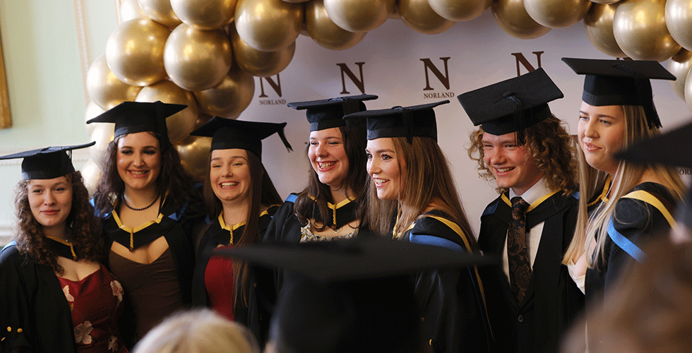 Norland degree graduates smiling for picture in front of balloons