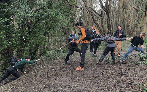 Photograph of students climbing steep hill and pulling one another up