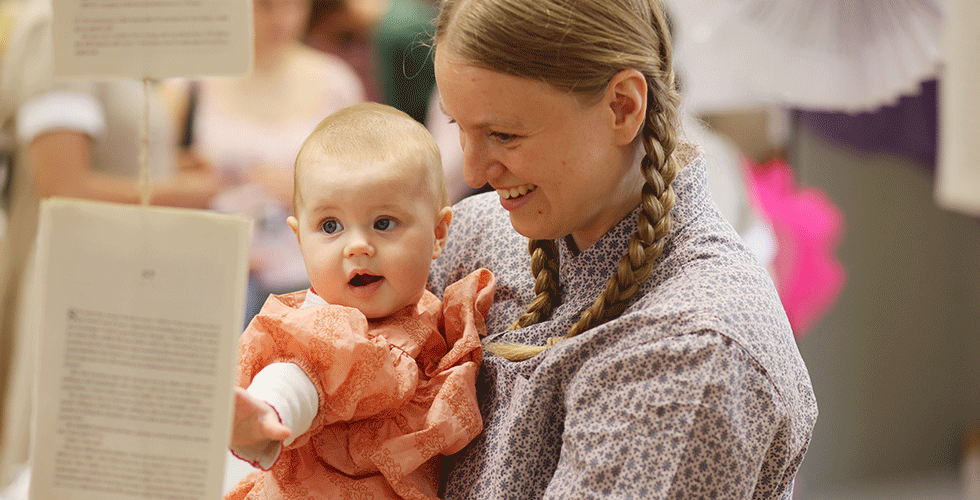 Norland Nanny holding baby looking at display