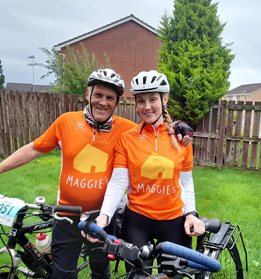A female and a male stood with bikes wearing a charity t shirt for the charity Maggie's
