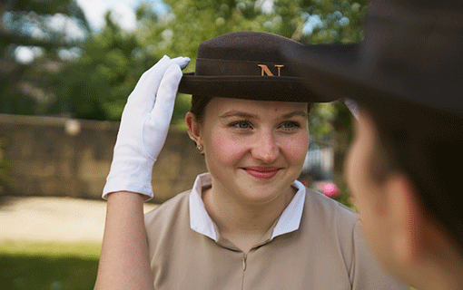 Norland student in uniform adjusting hat