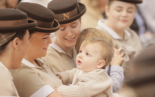 Norland students in uniform holding smiling baby