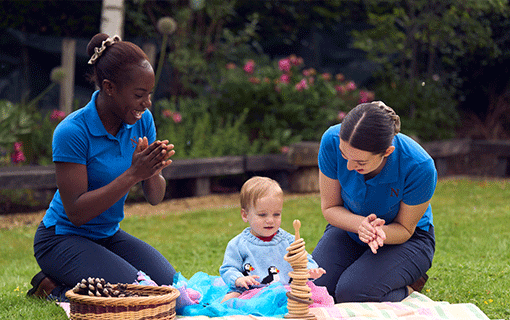 Norland students playing outside with baby in garden
