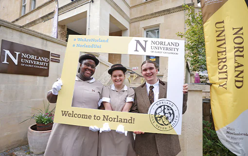 Three Norland University students smiling while holding a frame that says Welcome to Norland University on it